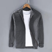 Cardigan grigio a coste per uomo, aperto, con maglietta bianca sotto, appeso su gruccia. Moda casual, abbigliamento autunnale, stile elegante.