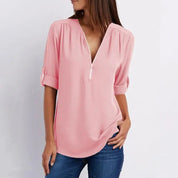 Blusa rosa donna con scollo a V e zip, maniche a 3/4, stile casual elegante, tessuto leggero, abbinata a jeans. Moda femminile primavera estate.