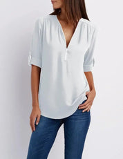 Blusa bianca da donna con scollo a V e maniche a tre quarti, abbinata a jeans blu. Elegante e casual, perfetta per ogni occasione.