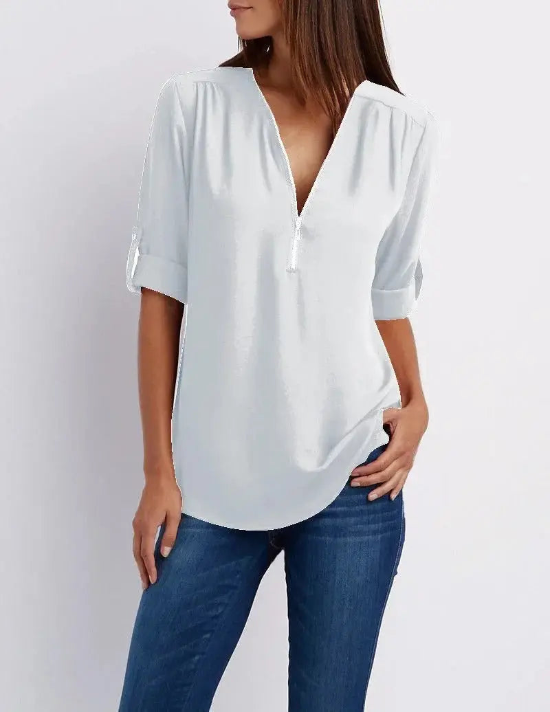 Blusa bianca da donna con scollo a V, maniche a tre quarti, abbinata a jeans blu. Elegante e casual, ideale per moda femminile quotidiana.