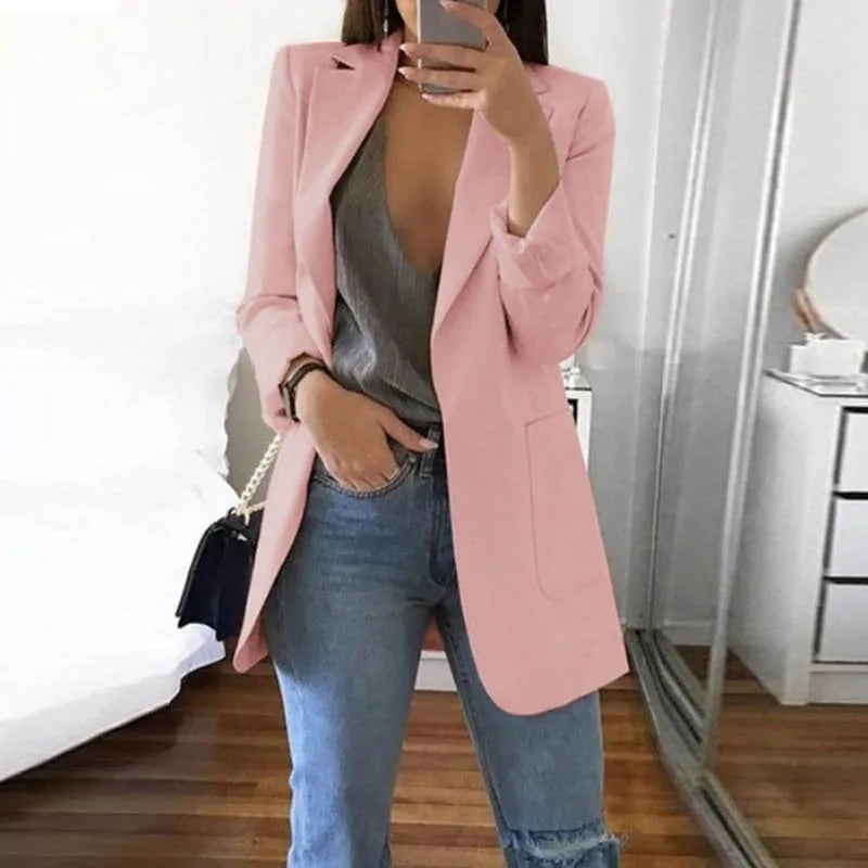 Donna con blazer rosa, top grigio e jeans strappati, specchio sullo sfondo. Moda casual elegante, abbigliamento femminile trendy.