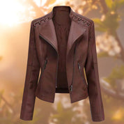 Giacca in pelle marrone da donna con cerniera frontale, dettagli intrecciati sulle spalle, sfondo sfocato naturale. Elegante e alla moda.