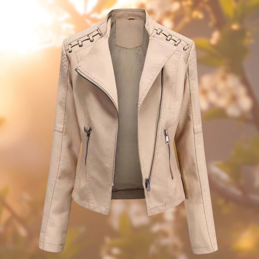 Giacca in pelle beige da donna con zip asimmetrica, dettagli intrecciati sulle spalle, sfondo sfocato autunnale. Moda femminile elegante.