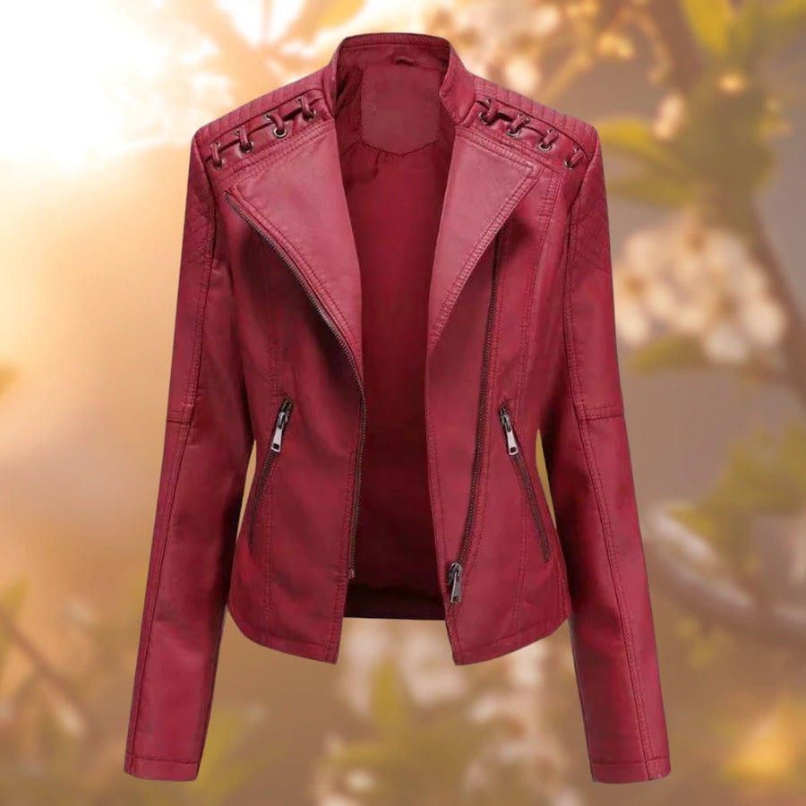 Giacca in pelle rossa da donna con cerniere e dettagli intrecciati sulle spalle, stile motociclista, sfondo sfocato autunnale.