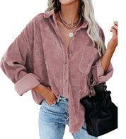 Donna con camicia di velluto a coste rosa, jeans blu e borsa nera. Moda autunnale, stile casual chic, abbigliamento femminile trendy.