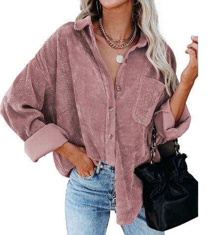 Donna con camicia di velluto a coste rosa, jeans blu e borsa nera. Moda autunnale, stile casual chic, abbigliamento femminile trendy.