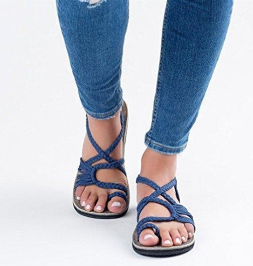 Jeans aderenti blu e sandali intrecciati blu su sfondo bianco. Scarpe estive eleganti, moda casual donna, calzature comode.