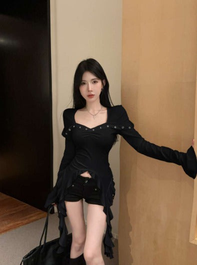 Donna in abito nero elegante con dettagli metallici, posa in interni moderni. Moda femminile, stile contemporaneo, abbigliamento trendy.