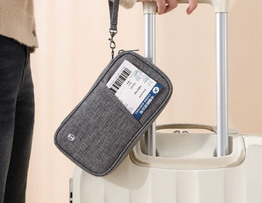 Portafoglio da viaggio grigio su valigia bianca, con biglietto aereo visibile. Accessorio essenziale per viaggiatori, pratico e funzionale.