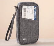 Custodia da viaggio grigia con cerniera, tasca frontale contenente un biglietto aereo. Design compatto, ideale per documenti e accessori da viaggio.
