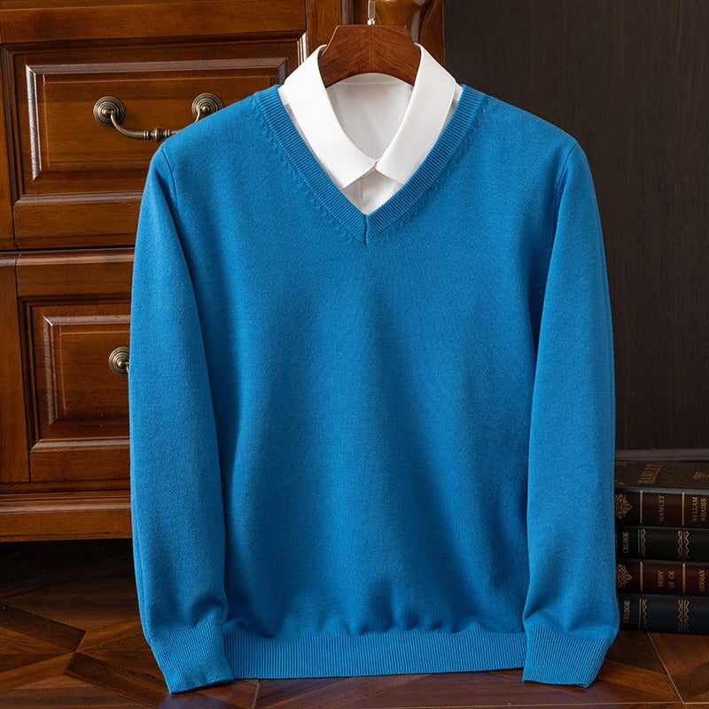 Maglione blu con scollo a V su camicia bianca, appeso su gruccia di legno. Moda uomo elegante, abbigliamento casual, sfondo con cassetti in legno.