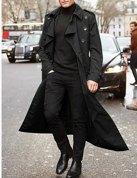 Uomo in cappotto nero lungo, maglione e pantaloni neri, stivali eleganti, cammina in città. Moda maschile, stile urbano, abbigliamento invernale.