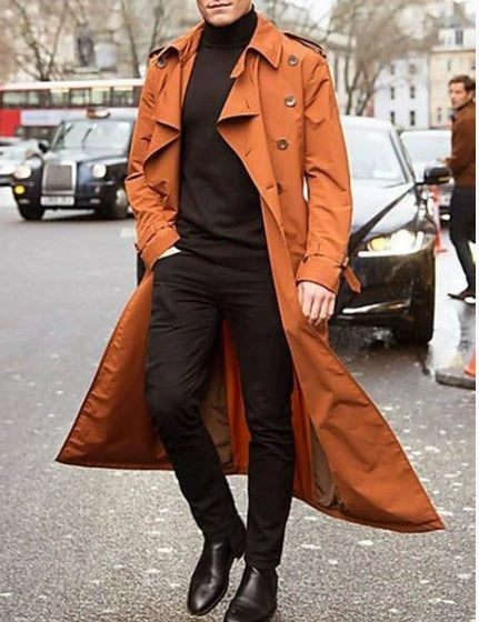 Uomo con trench marrone su strada cittadina, indossa dolcevita nero e pantaloni scuri. Moda autunnale, stile urbano elegante.