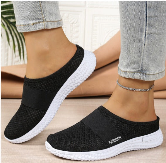 Scarpe slip-on nere da donna con suola bianca, indossate con jeans chiari. Design casual e moderno, perfette per passeggiate e tempo libero.