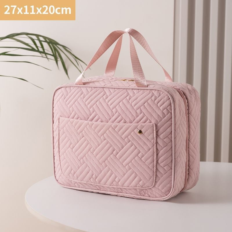 Borsa da viaggio rosa trapuntata, dimensioni 27x11x20 cm, con manici e tasca frontale, su tavolo bianco. Accessorio elegante e pratico.