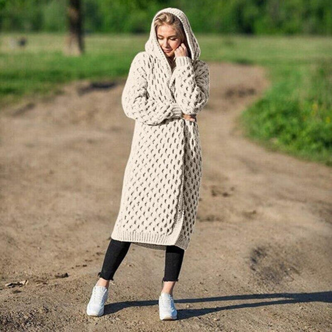 Donna con cardigan lungo a maglia beige con cappuccio, su strada sterrata. Moda autunnale, abbigliamento casual, stile confortevole.