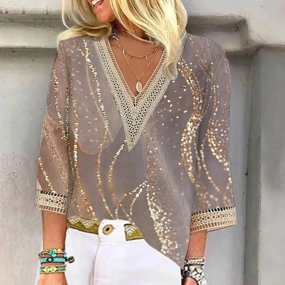Blusa donna elegante con paillettes dorate, maniche a 3/4, scollo a V, dettagli in pizzo, abbinata a pantaloni bianchi. Moda femminile chic.