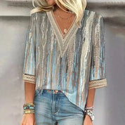 Blusa donna elegante con paillettes, maniche a tre quarti, scollo a V, dettagli in pizzo, colori blu e argento, abbinata a jeans casual.