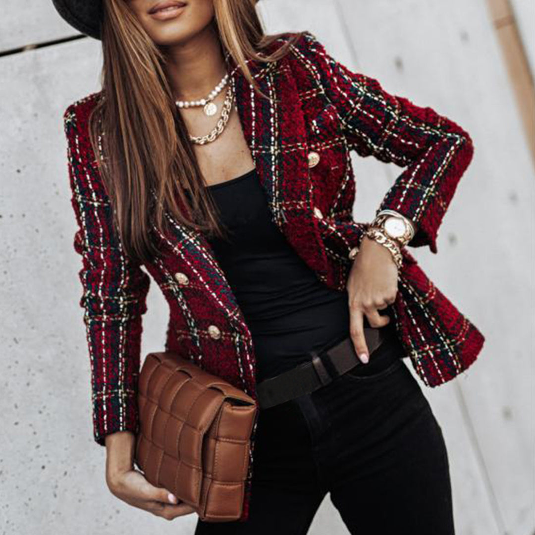 Giacca a quadri rossa elegante, donna con borsa trapuntata marrone, collana di perle e orologio dorato. Moda autunnale chic e sofisticata.
