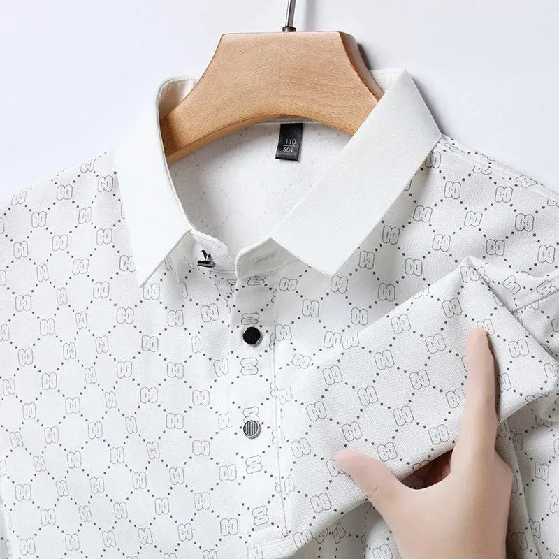 Camicia bianca a maniche lunghe con motivo geometrico, colletto classico e bottoni neri, appesa su gruccia di legno. Tessuto elegante e moderno.
