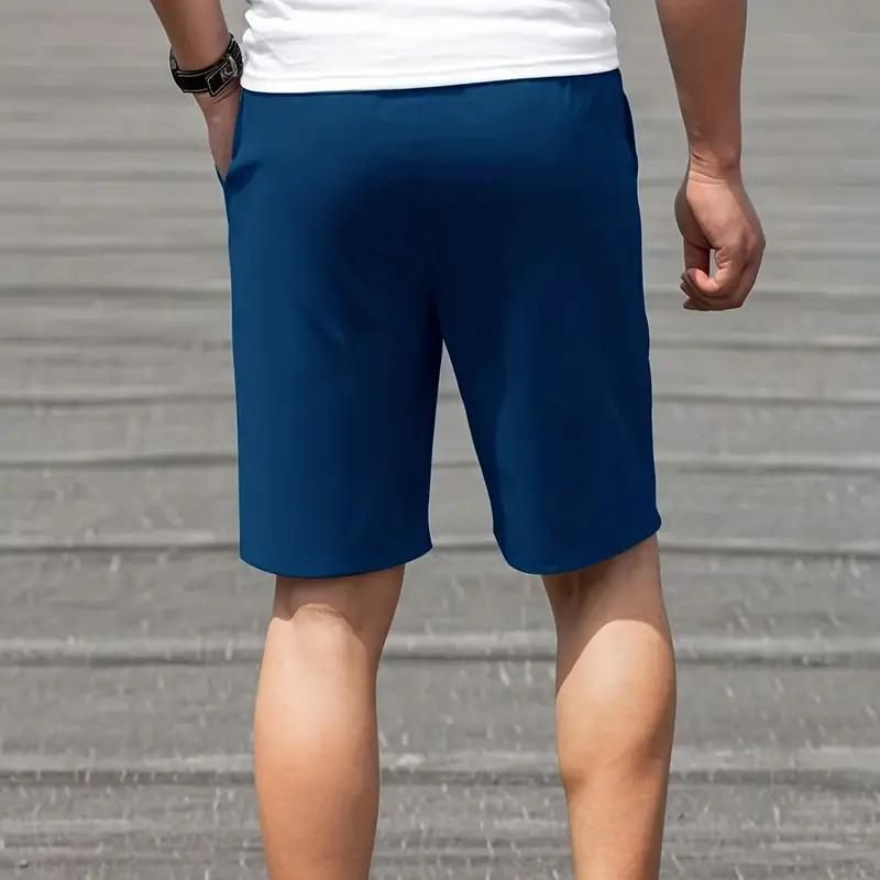 Uomo in pantaloncini blu sportivi, vista posteriore, su strada asfaltata. Abbigliamento casual estivo, moda maschile, comfort e stile.