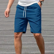 Pantaloncini sportivi blu da uomo con coulisse, tasche laterali, indossati con maglietta bianca. Ideali per attività sportive e tempo libero.