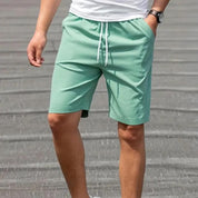 Pantaloncini uomo verde menta, casual, con coulisse, indossati da modello. Ideali per estate, moda maschile, abbigliamento sportivo.