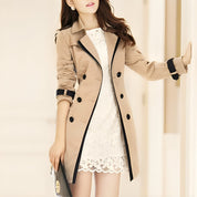 Cappotto trench beige da donna, doppio petto, dettagli neri, abbinato a vestito bianco in pizzo. Elegante moda autunnale.