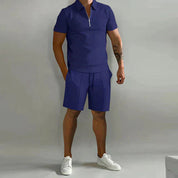 Completo estivo uomo blu, polo con zip e pantaloncini, stile casual, tessuto leggero, ideale per moda estiva, abbinato a scarpe bianche.