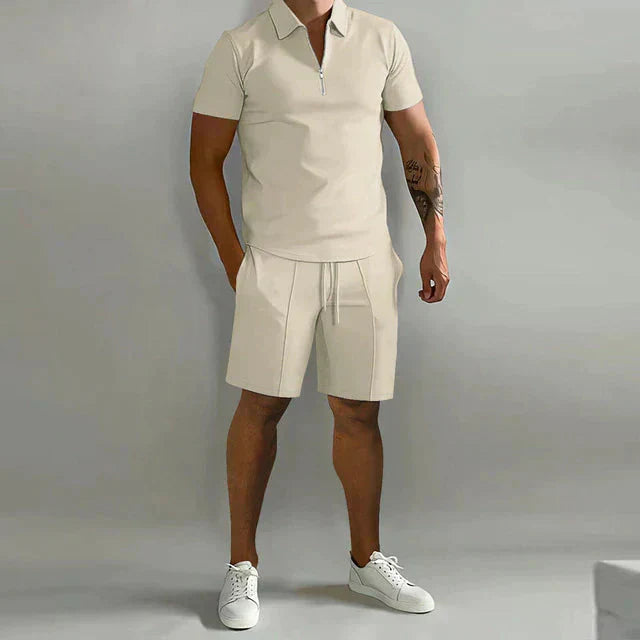 Uomo in completo estivo beige, polo con zip e pantaloncini, scarpe da ginnastica bianche. Moda casual maschile, abbigliamento estivo elegante.