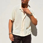 Camicia estiva uomo in maglia traforata beige, maniche corte, abbinata a pantaloni scuri. Stile casual elegante, ideale per moda estiva.