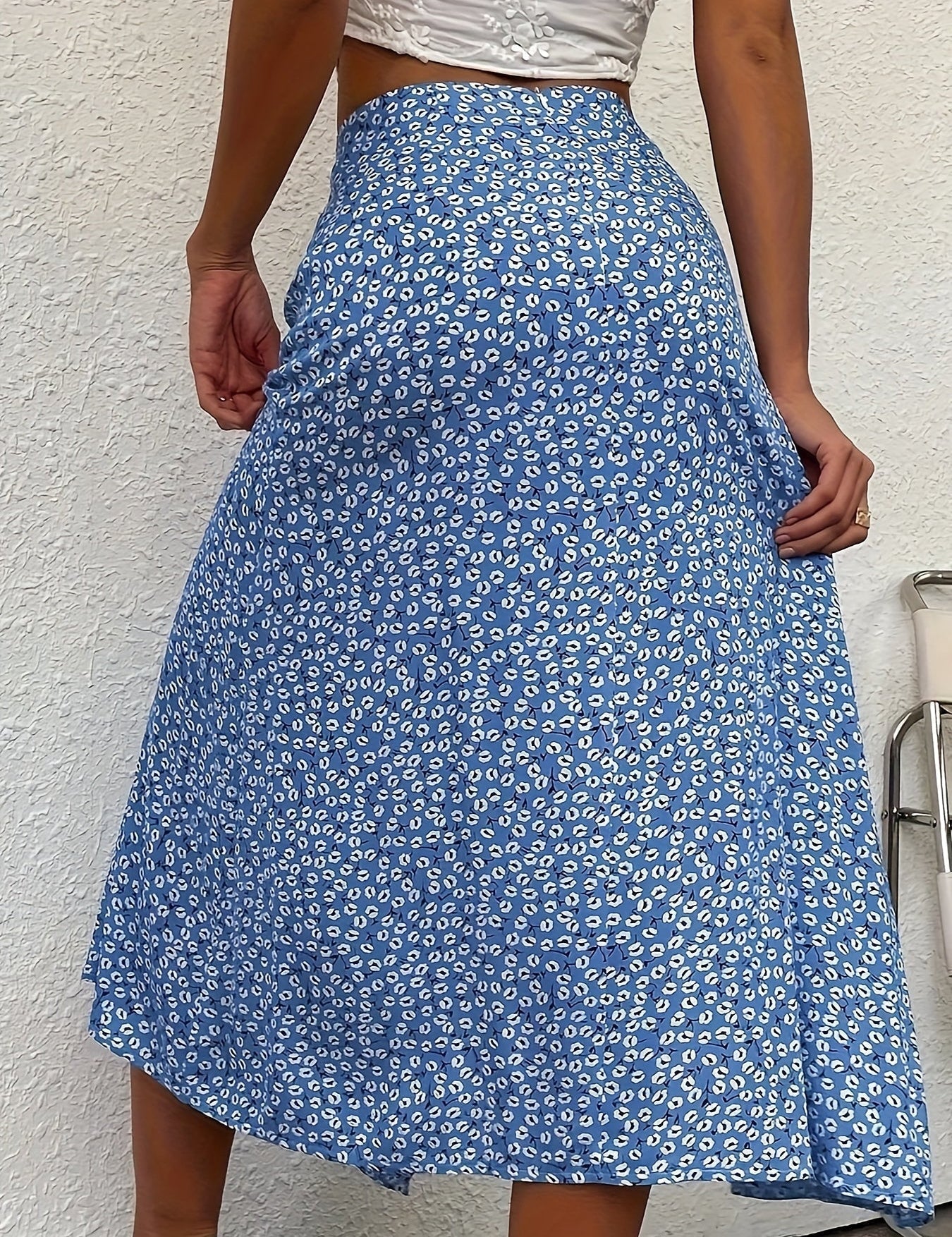 Gonna lunga blu a fiori bianchi, indossata da una donna, su sfondo bianco. Moda estiva, abbigliamento femminile elegante e casual.