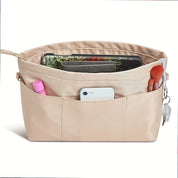 Organizzatore borsa beige con tasche multiple, contenente smartphone, pennello trucco, rossetto e chiavi. Accessorio pratico per borse da donna.