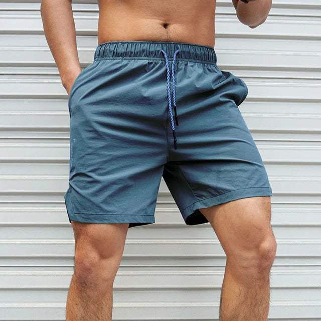 Shorts sportivi da uomo blu, elastico in vita con cordino, indossati da modello su sfondo bianco. Ideali per palestra, corsa, fitness.