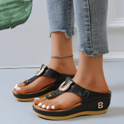 Sandali donna neri con zeppa, cinturino regolabile, dettagli dorati, indossati con jeans. Scarpe estive eleganti e comode per ogni occasione.