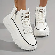 Scarpe da ginnastica bianche con suola spessa, dettagli neri e cerniera laterale. Design moderno e alla moda per un look casual e sportivo.