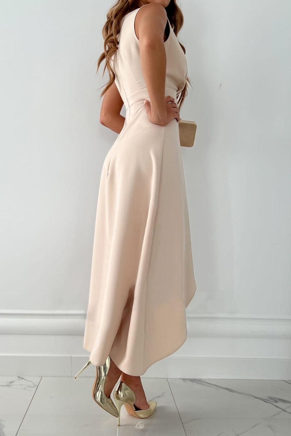 Abito elegante donna color crema, lunghezza midi, senza maniche, con spacco laterale. Scarpe col tacco dorate. Moda femminile chic.