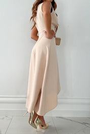 Abito elegante donna color crema, lunghezza midi, senza maniche, con spacco laterale. Scarpe col tacco dorate. Moda femminile chic.