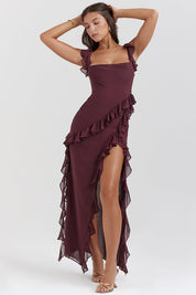 Abito lungo elegante bordeaux con balze, spalline sottili e spacco laterale. Perfetto per eventi serali e cerimonie. Moda donna sofisticata.