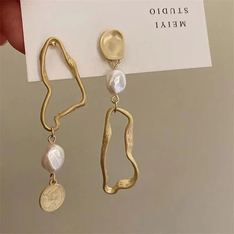 Orecchini pendenti asimmetrici in oro con perle irregolari e moneta, design moderno, gioielli artigianali eleganti, accessori moda donna.