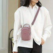 Donna con camicia bianca indossa borsa a tracolla rosa, piccola e compatta, ideale per moda casual. Accessorio trendy per look quotidiano.