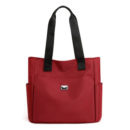 Borsa tote rossa elegante con manici neri, tasche laterali e logo frontale. Perfetta per moda donna, shopping e uso quotidiano.