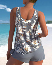 Donna in spiaggia con canotta floreale grigia e pantaloncini coordinati. Moda estiva, abbigliamento casual, look da vacanza al mare.