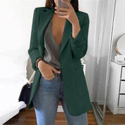 Giacca verde elegante da donna, abbinata a top grigio e jeans, moda casual chic, perfetta per look autunnali.