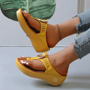 Sandali gialli da donna con zeppa, cinturino regolabile e logo, indossati con jeans. Scarpe estive moda, comode e trendy.