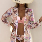 Cappello di paglia con scritta, costume da bagno rosa e copricostume floreale. Moda estiva donna, abbigliamento mare elegante e trendy.