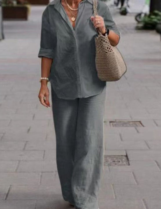 Donna con camicia e pantaloni grigi, borsa a maglia beige, cammina su marciapiede. Moda casual, abbigliamento estivo, accessori eleganti.