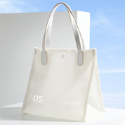 Borsa tote bianca trasparente con manici in pelle, design moderno, ideale per shopping e viaggi. Sfondo blu cielo. Accessorio moda elegante.