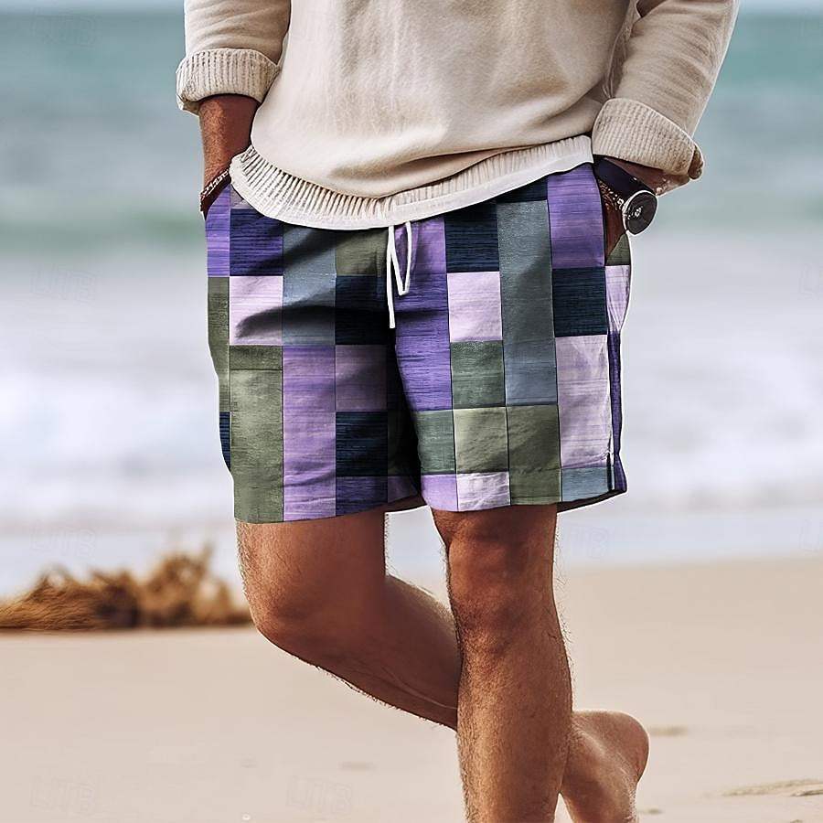 Uomo in spiaggia con pantaloncini a quadri multicolore, maglione beige, orologio nero. Moda estiva casual, abbigliamento maschile trendy.