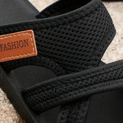 Sandalo nero da uomo in tessuto traspirante con etichetta marrone "FASHION", suola robusta, ideale per l'estate e il tempo libero.